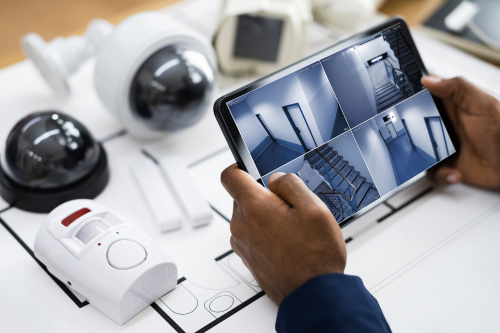 Professional alarm system equipment including motion sensors, surveillance cameras, and smart monitoring tablet