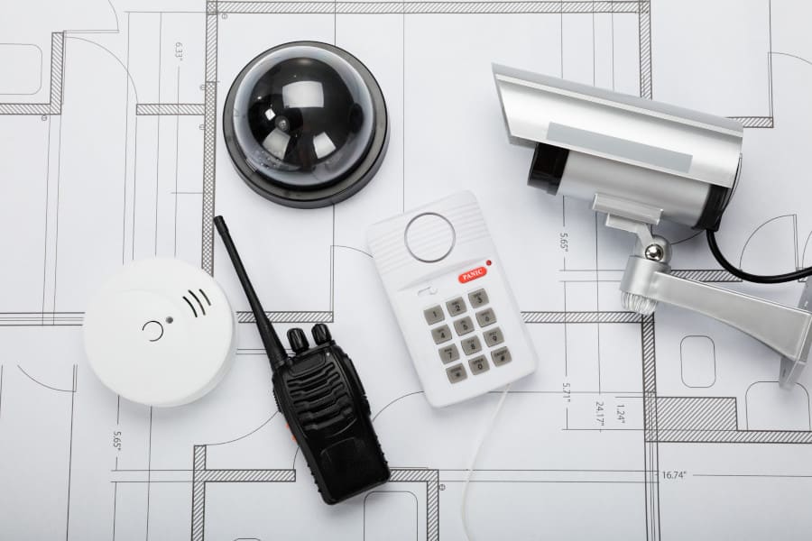 Commercial alarm keypad, dome camera and security equipment laid out on building blueprints